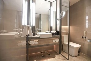 A modern bathroom with a glass shower enclosure, a sink, a toilet, and a mirror. - Future Hotel (Zhengzhou)