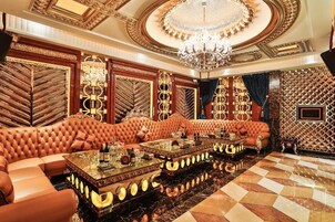 A luxurious room with a large sofa, a chandelier, and a patterned wall.