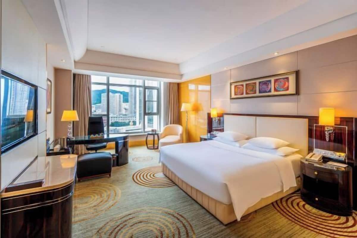 Una habitación de hotel con una cama grande, un escritorio, una silla y un televisor.
