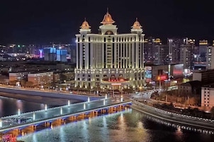Un hotel grande e iluminado con tres torres y un río al frente.