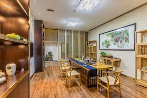 Un comedor con una mesa larga, sillas, piso de madera y un cuadro en la pared.