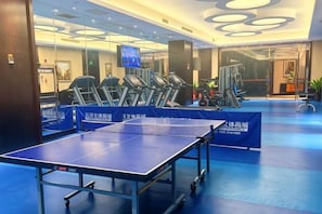 A gym with exercise equipment, a ping pong table, and a reception area.