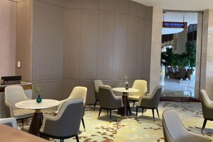 A hotel lobby with seating arrangements, a reception desk, and a visible entrance to another area.