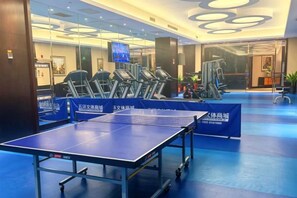 Un gimnasio con equipo de ejercicio y una mesa de ping pong.