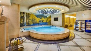 Un espace spa comprenant un jacuzzi, une fresque murale et un plafond au design unique.