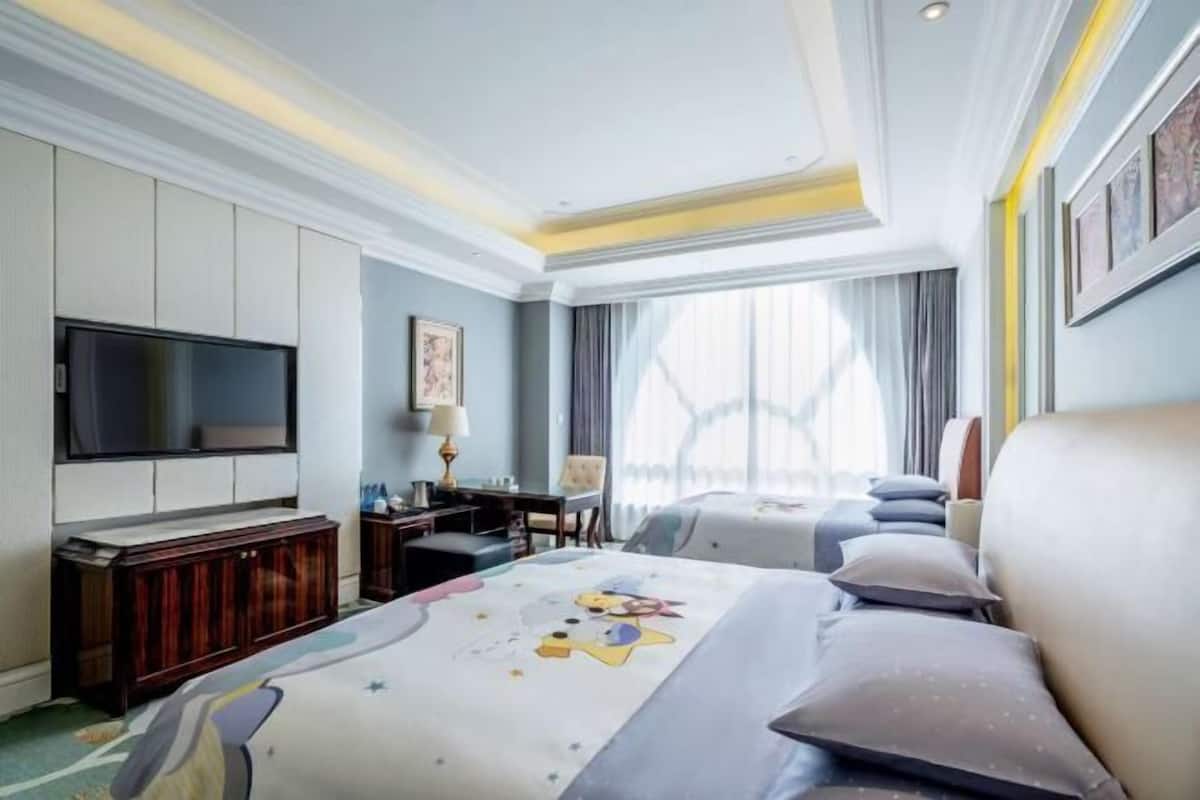 Habitación de hotel con una cama grande, televisor de pantalla plana, escritorio y ventana con cortinas.