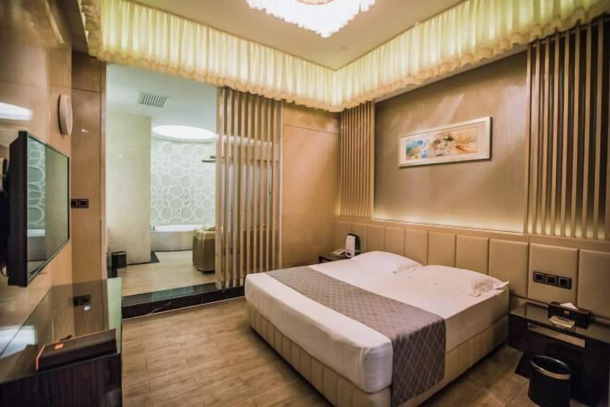 Una habitación de hotel con una cama grande, una mesita de noche y un espejo.