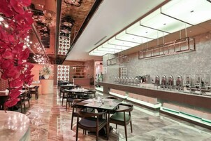 Un restaurante moderno con área de bar, disposición de asientos y una pared decorativa con diseño geométrico.