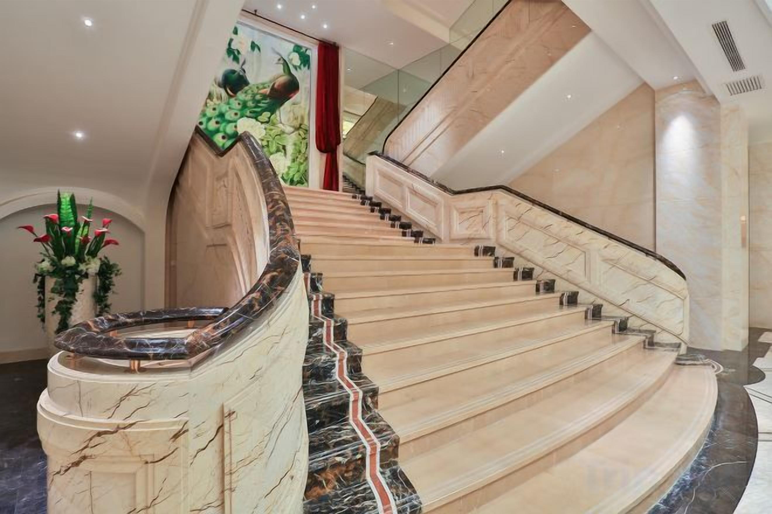 A grand staircase with marble steps and a curved handrail, leading to an upper floor.