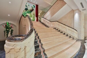 Una imponente escalera con escalones de mármol y una barandilla curva, que conduce a un piso superior.