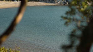 Ein ruhiger See mit steiniger Uferlinie und spärlicher Vegetation.