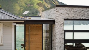 Ein modernes Gebäude mit einer Stein-Fassade, großen Fenstern und einer Solaranlage auf dem Dach.