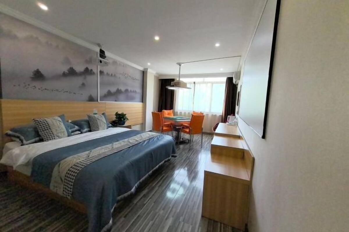 Una habitación de hotel con cama, escritorio, silla y un gran ventanal.
