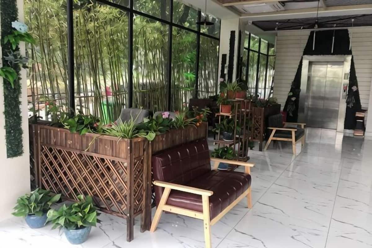 Un vestíbulo con un banco de madera, plantas en macetas y un piso de mármol.