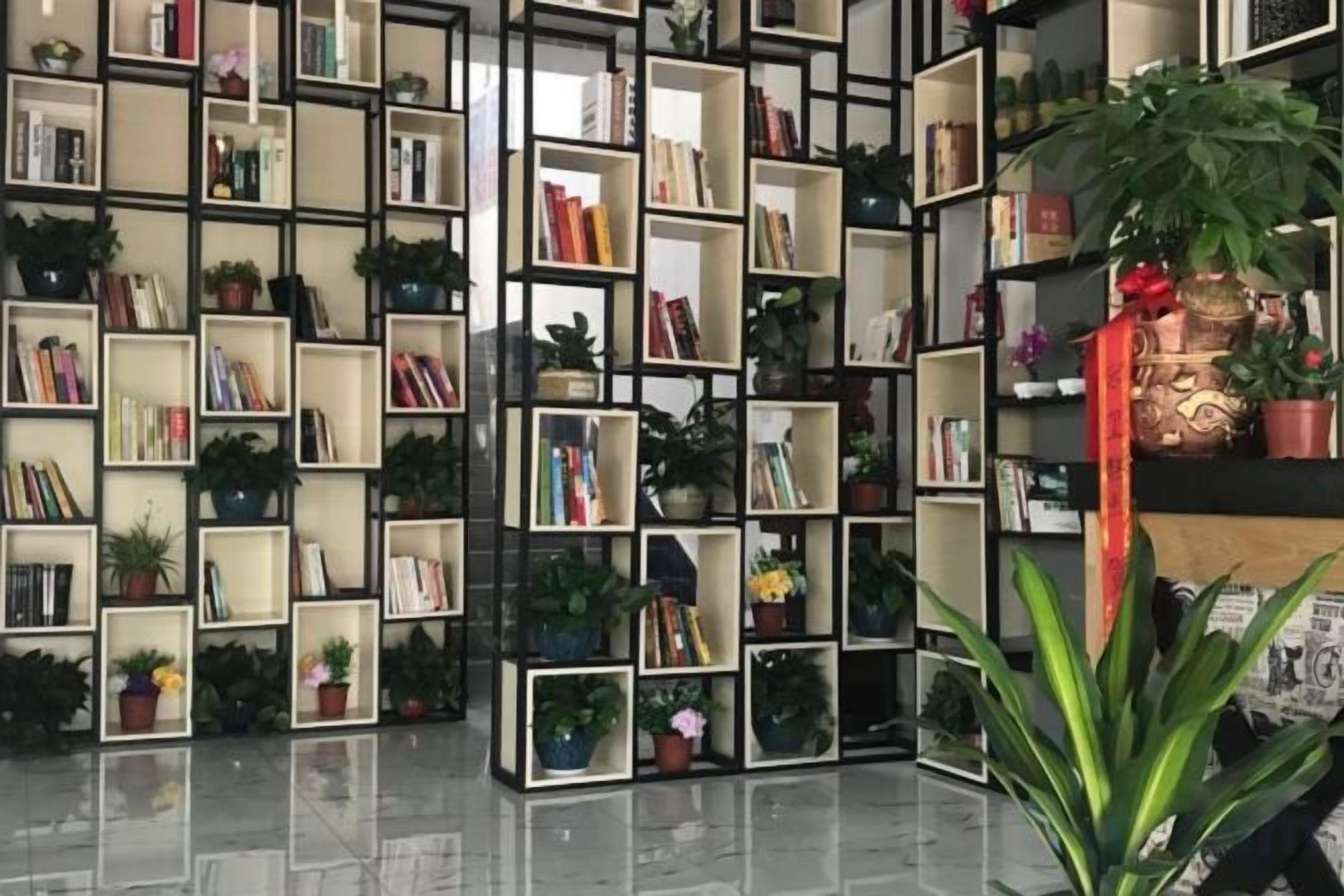 A library with multiple bookshelves filled with books and potted plants.