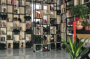 Una biblioteca con varias estanterías llenas de libros y plantas en macetas.
