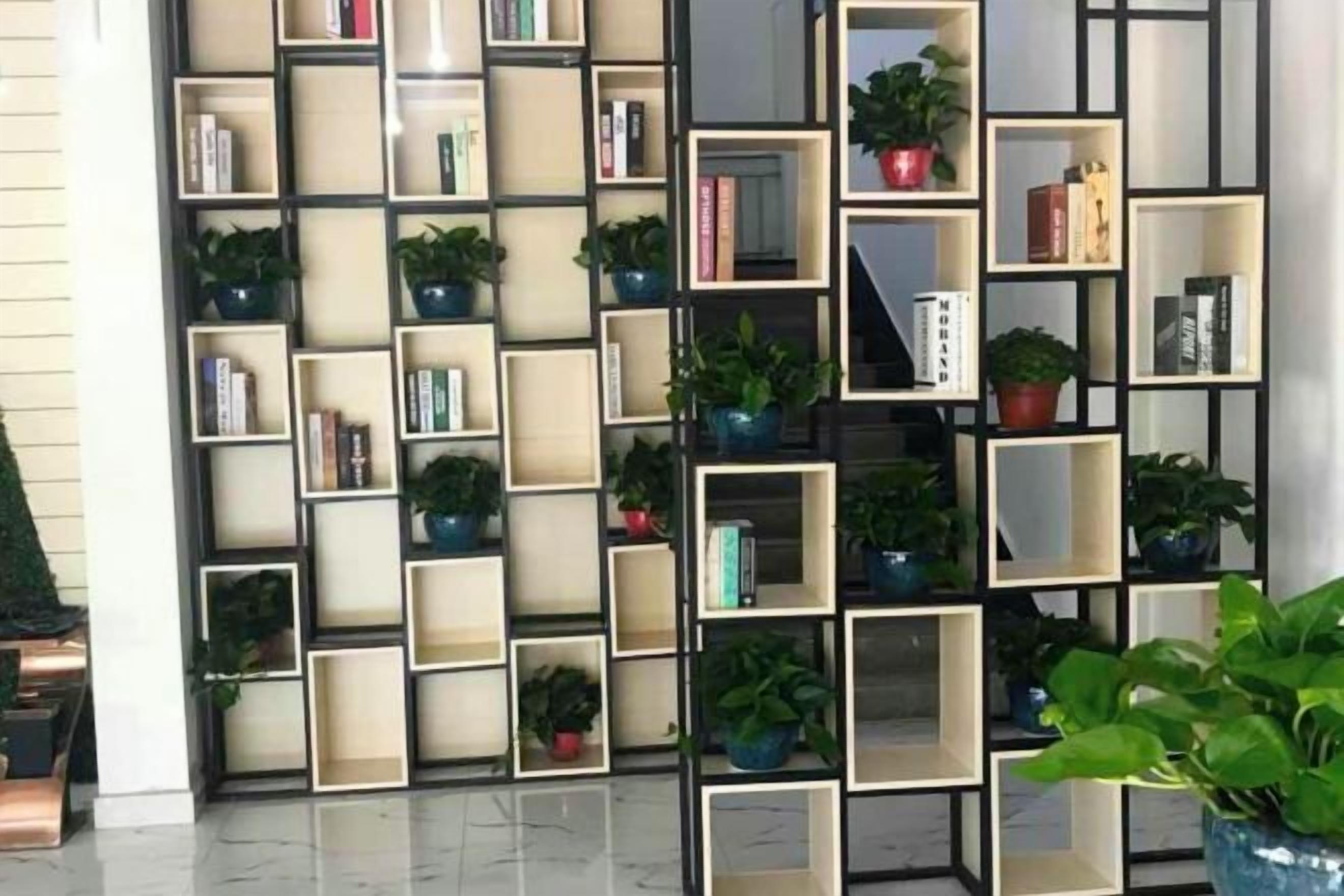 Una pared con varias estanterías que contienen libros y plantas en macetas.