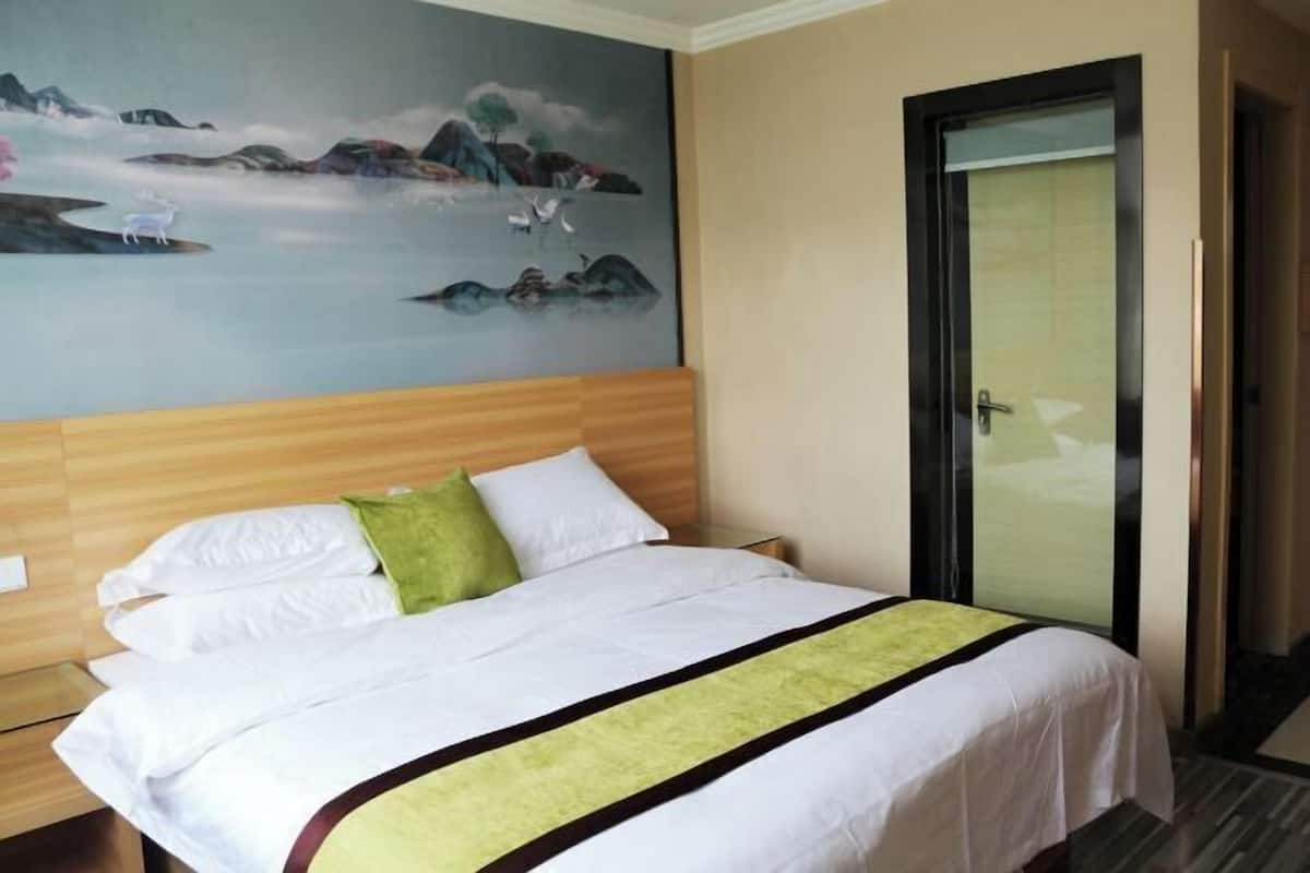 Una habitación de hotel con una cama, un cuadro en la pared y una puerta.