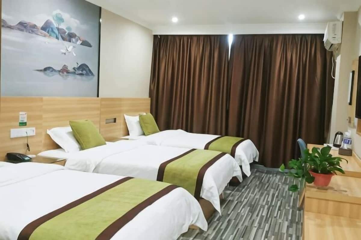 Habitación de hotel con dos camas, un escritorio, una silla, una planta y un cuadro en la pared.