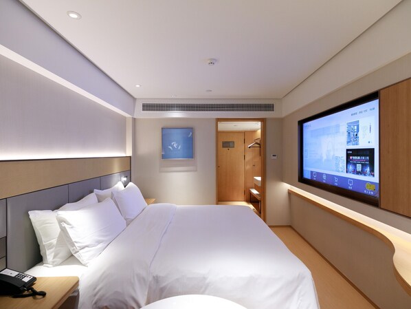 A hotel room with a bed, a TV, a phone, and a door leading to a bathroom. - Ji Hotel (Shanghai)