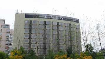 Um edifício com vários andares, teto plano, inúmeras janelas e uma placa que indica ser um hotel.