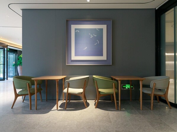 A modern interior with a framed artwork, wooden tables, and chairs. - Ji Hotel (Shanghai)