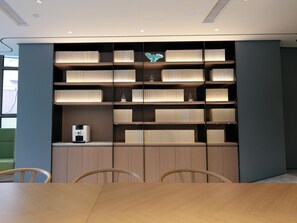 A modern interior with a wooden table and chairs, a built-in bookshelf with decorative items, and a window with a view. - Ji Hotel (Shanghai)