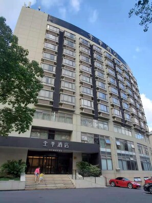 Un hôtel à plusieurs étages, doté d’une entrée imposante, de balcons et offrant une vue sur un ciel dégagé.
