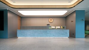 En moderne receptionsdisk, et skilt med kinesiske tegn på væggen og et rent, minimalistisk interiør.