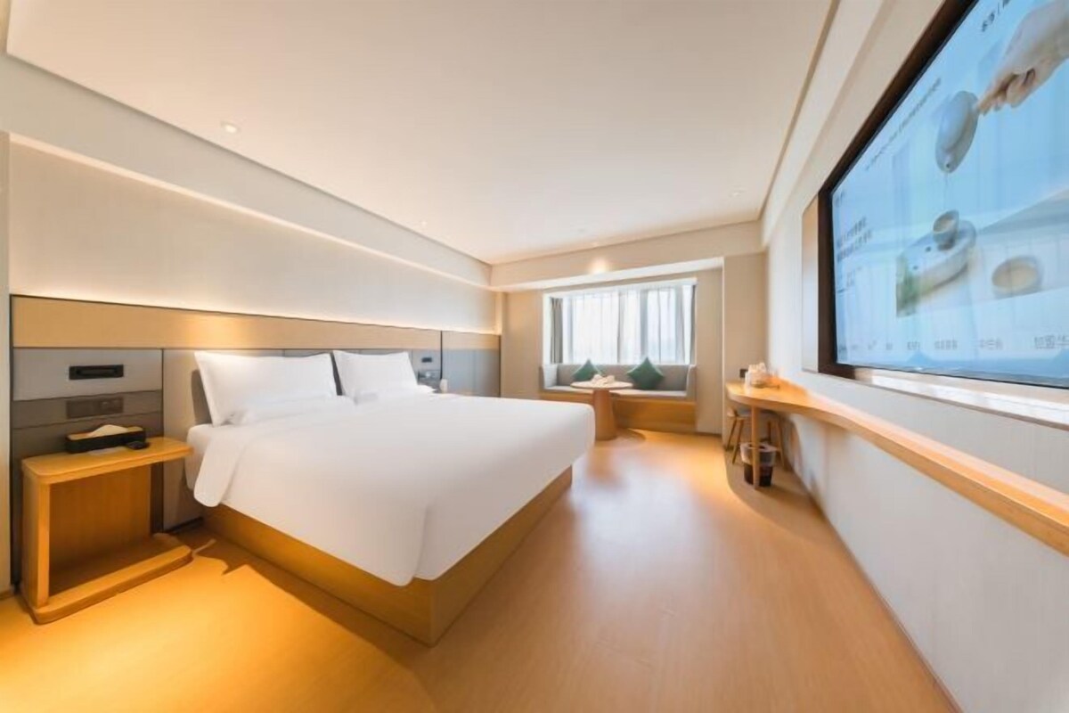 Une chambre d’hôtel moderne avec un grand lit, une table de chevet et une fenêtre donnant sur un beau paysage.