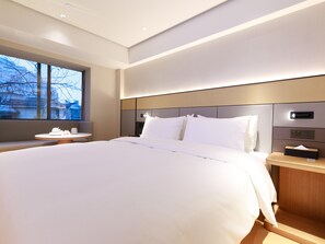 Une chambre d’hôtel moderne, dotée d’un grand lit, de tables de chevet, d’une fenêtre offrant une vue agréable et d’un panneau de commande mural.