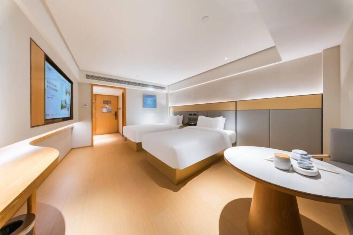 A modern hotel room with a large bed, a desk, and a television.