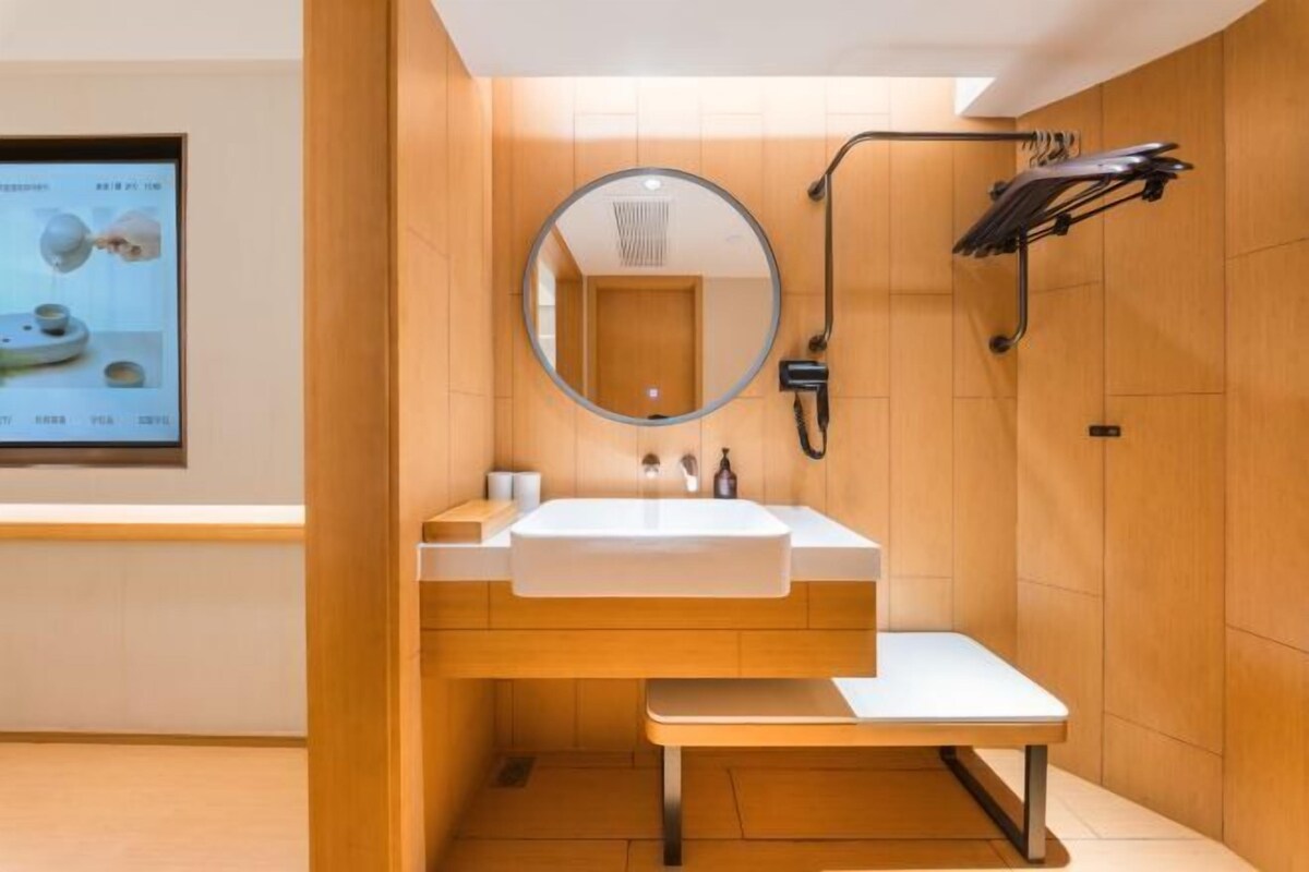 Une salle de bain moderne équipée d’un lavabo, d’un miroir, d’un porte-serviettes et d’un espace douche.