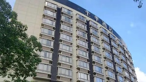 Et hotel med flere etager, en markant indgang, altaner og en klar himmel.
