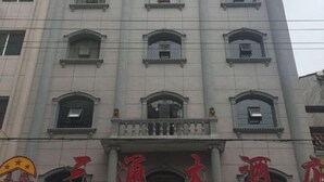 A building with multiple windows and a large sign with Chinese characters. - Santong Hotel (Shimen)