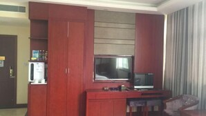 A room with a wooden cabinet, a television, and a small table with chairs. - Santong Hotel (Shimen)