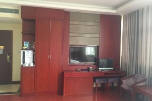 Una habitación con un armario de madera, un televisor y una pequeña mesa con sillas.