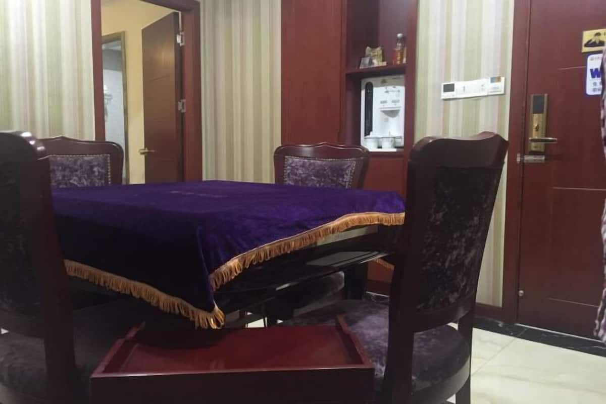 A room with a wooden dining table, purple tablecloth, and matching chairs.