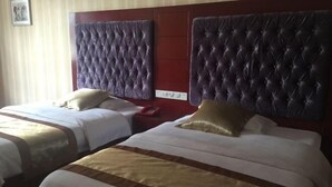 A hotel room with two beds, each with a tufted headboard and a striped bedspread. - Santong Hotel (Shimen)