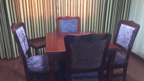 A dining area with a wooden table and four upholstered chairs with patterned fabric. - Santong Hotel (Shimen)