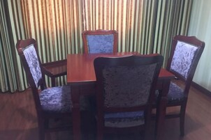 Comedor con mesa de madera y cuatro sillas tapizadas con tela estampada.