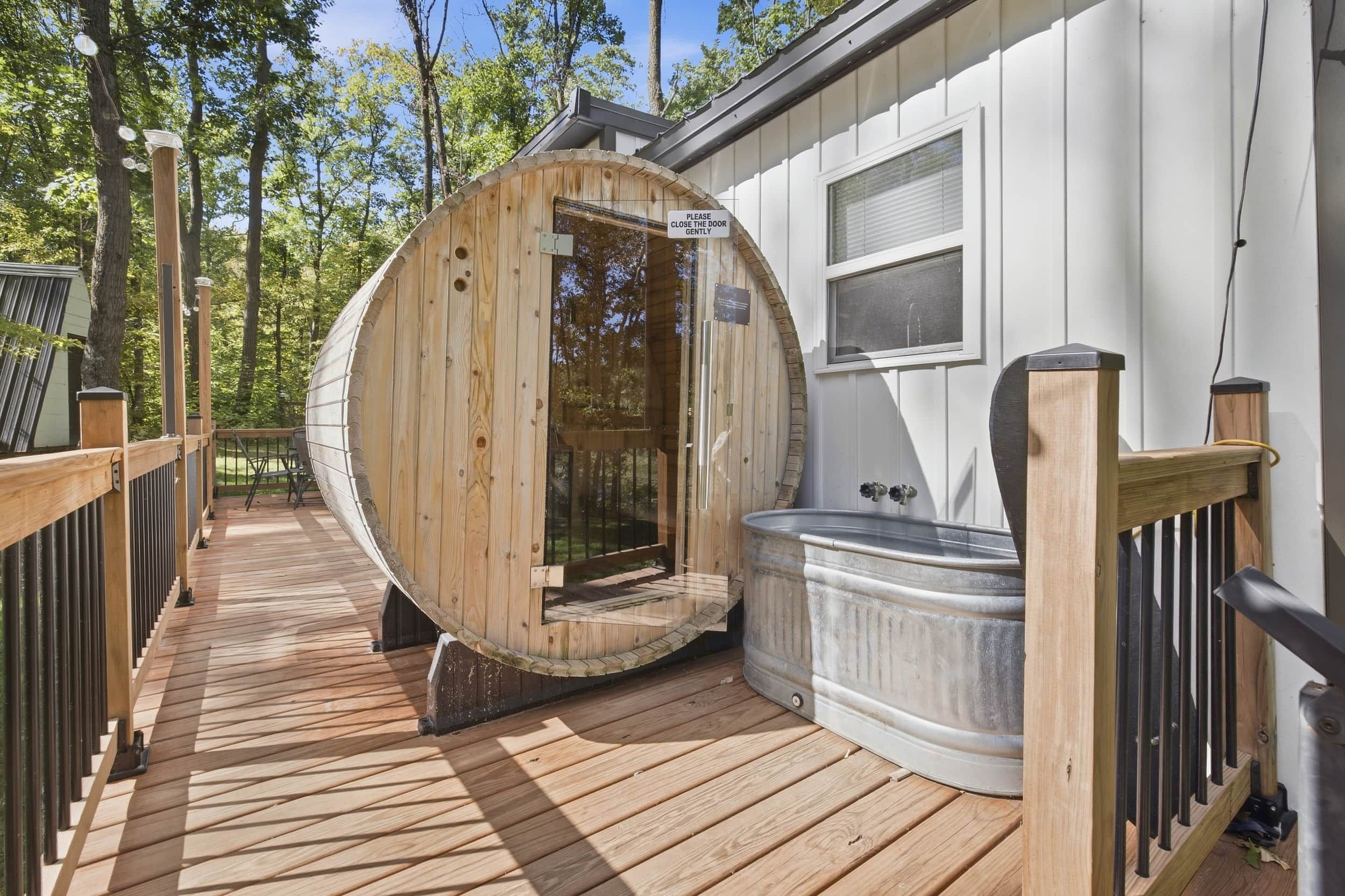 A wooden sauna with a door, a hot tub, and a wooden deck.