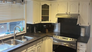 A modern kitchen with white cabinetry, stainless steel appliances, and a black countertop.