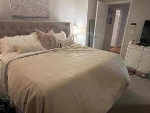 A bedroom with a large bed, a headboard, and a television on a cabinet. - Kid friendly House on the park (Burnaby)