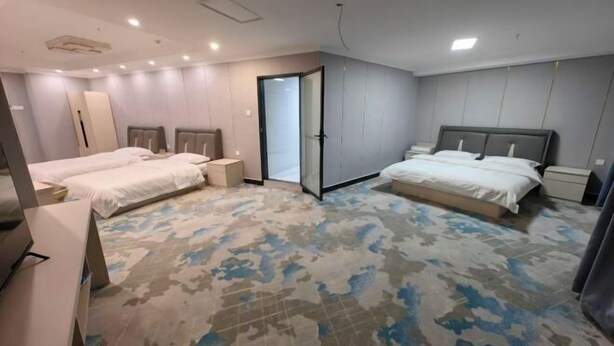 A hotel room with two beds, a large mirror, and a patterned carpet. - Zihao Hotel (Hunchun Yifen) (Hunchun)