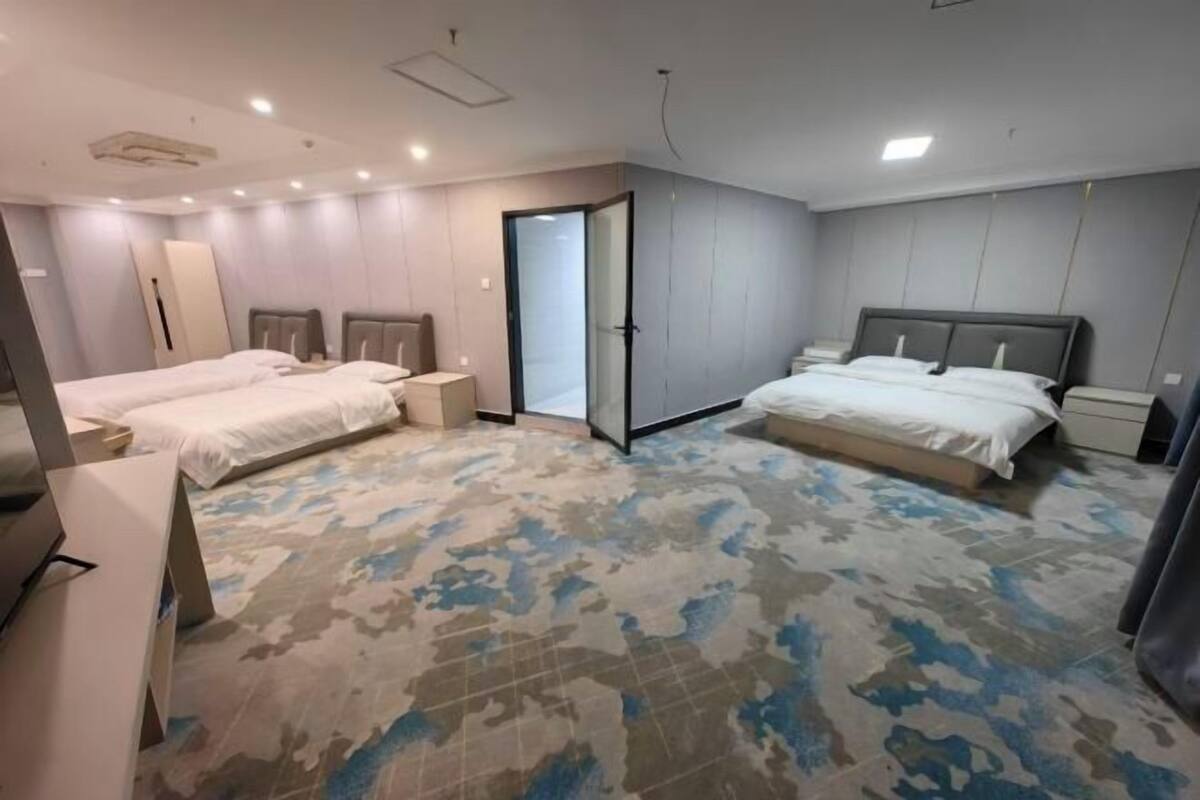 A hotel room with two beds, a large mirror, and a patterned carpet.