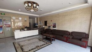 A modern lobby with a reception desk, a brown leather sofa, a patterned rug, and a marble wall. - Zihao Hotel (Hunchun Yifen) (Hunchun)