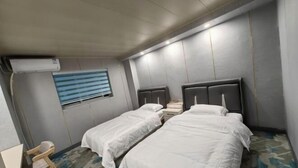 A hotel room with two single beds, a small desk, and a window with blinds. - Zihao Hotel (Hunchun Yifen) (Hunchun)