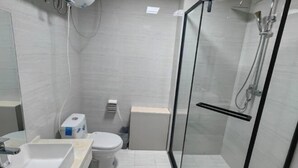 A modern bathroom with a glass-enclosed shower, a white sink, and a toilet. - Zihao Hotel (Hunchun Yifen) (Hunchun)