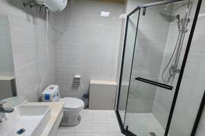 Un baño moderno con ducha de vidrio, un lavamanos blanco y un inodoro.